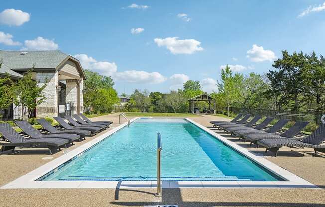 A large rectangular pool with a diving board in the middle surrounded by lounge chairs.