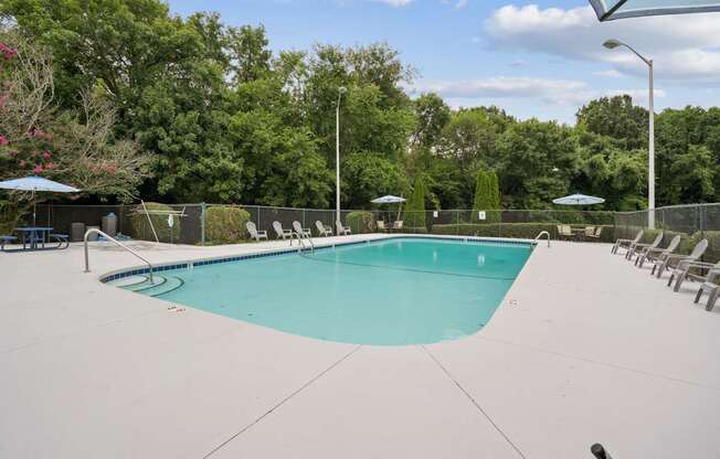 A large swimming pool surrounded by trees and chairs.