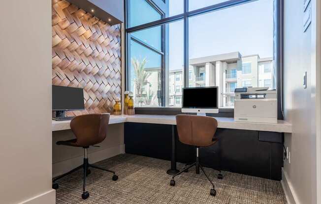 A modern office with two chairs and a desk with a computer.