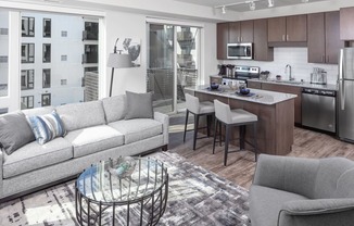 a living room and kitchen space with a white couch and counter stools at Maven on Broadway, Rochester, MN