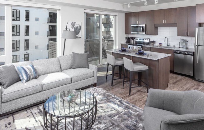 a living room and kitchen space with a white couch and counter stools at Maven on Broadway, Rochester, MN