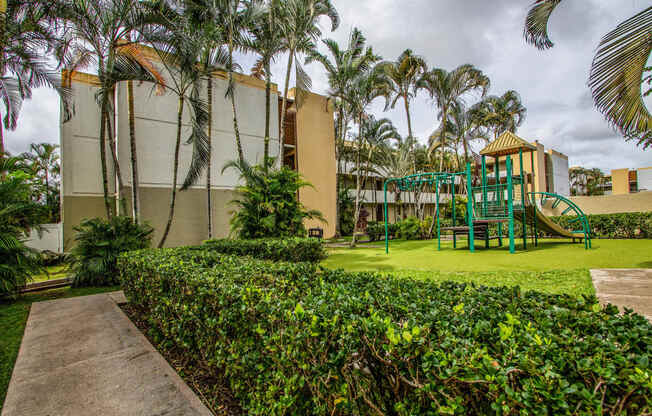 a playground with palm trees in front of a building at Palms of Kilani Apartments, Wahiawa, HI, 96786