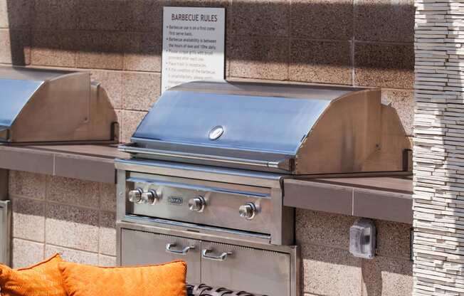 a bbq pit area with a wicker chair and orange cushions