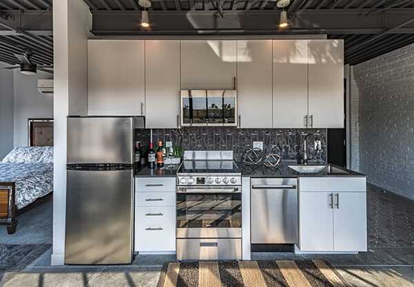 Steelcote Crossing kitchen with white cabinetry, black quartz countertops, stainless steel appliances, black tile backsplash and concrete floors at Steelcote Square, Missouri, 63103