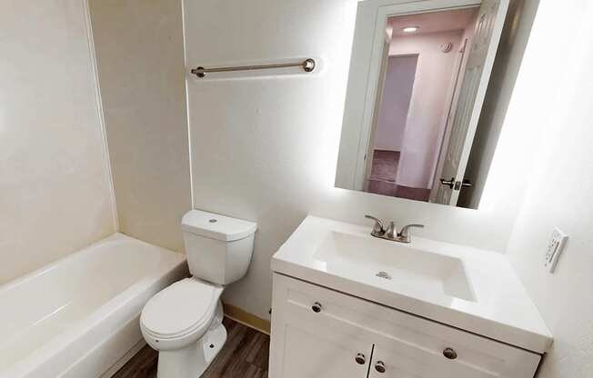 A white bathroom with a toilet, sink, and bathtub.