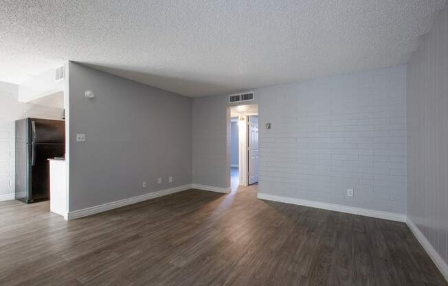 an empty living room with wood floors and a white brick wall