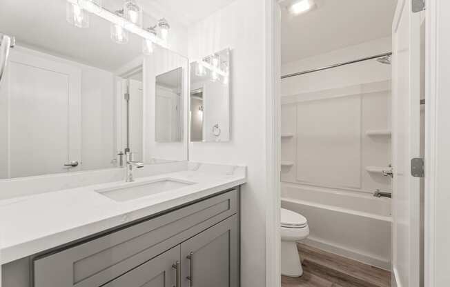 A white bathroom with a sink, mirror, and toilet.