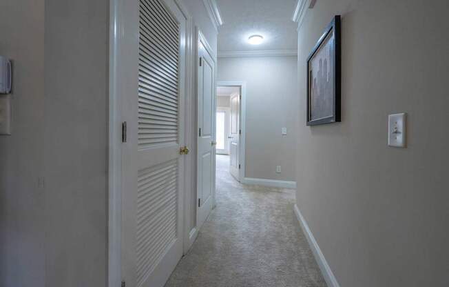 A hallway with a light on the wall and a painting hanging above it.