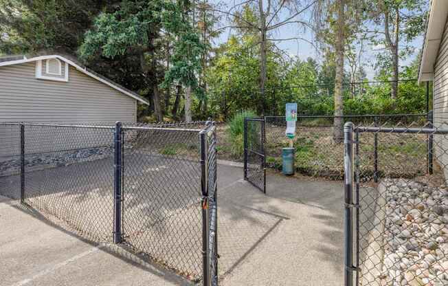 A fenced in pet area with a pet waste station at Abbey Rowe Apartments in Olympia, WA