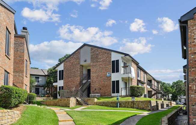 An apartment building with green lawns in front at The Oaks of Denton Apartments in Denton, TX