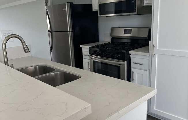 an empty kitchen with white cabinets and a sink