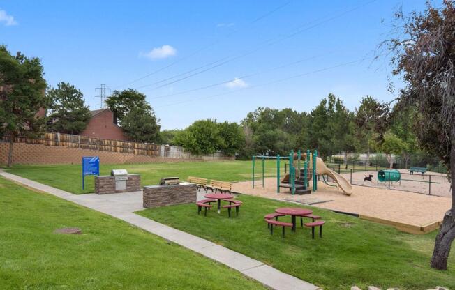 A playground with a slide, swings, and picnic tables.