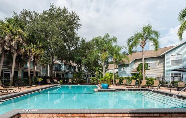 a swimming pool with palm trees in front of apartment buildings