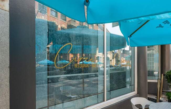 A blue umbrella is covering a table outside of a restaurant.