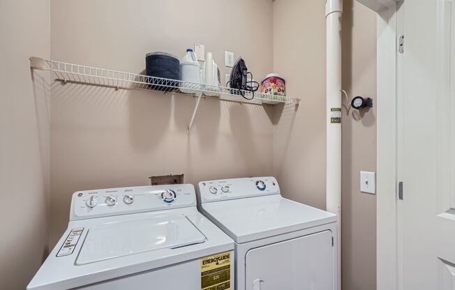 a washer and dryer in a laundry room with a shelf above them