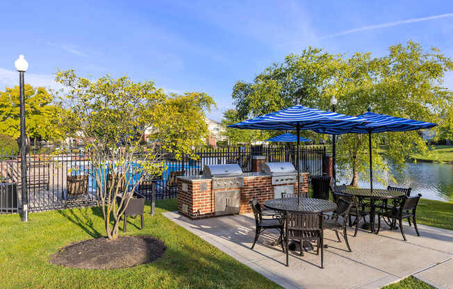 a patio with tables and umbrellas next to a body of water