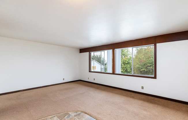 an empty living room with a large window and white walls