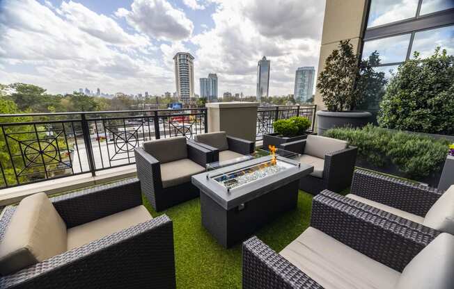 a patio with a fire pit and seating on a balcony with a view of the city