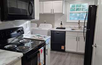 A black stove top oven with a white stove top and a black microwave above it.