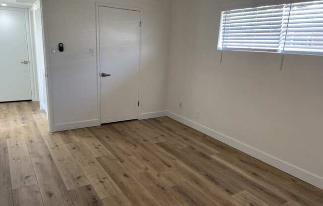 a bedroom with wooden floors and white walls and a door