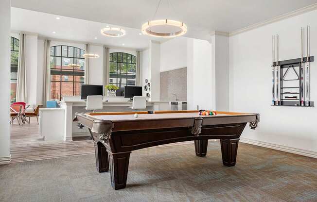 A pool table is in the middle of a room with a white ceiling and a window.