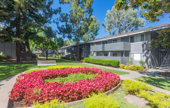 A garden with a lot of flowers in the foreground and a building in the background.