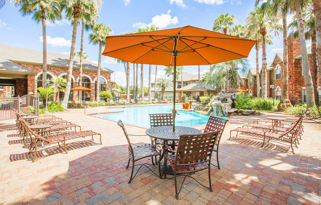 a patio with a table and chairs under an orange umbrella