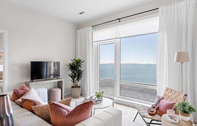 A living room with a large window overlooking the water.