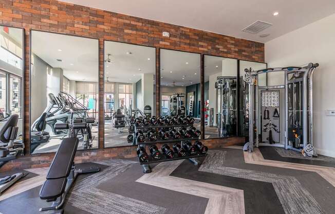 A gym with a variety of equipment including weights and cardio machines.