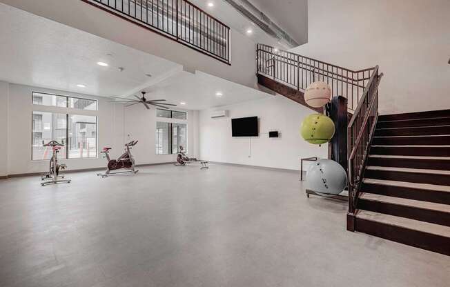 the gym has a staircase and a large room with treadmills and exercise balls