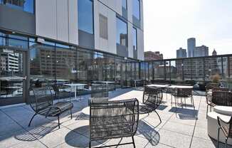 a rooftop patio with tables and chairs and a city in the background