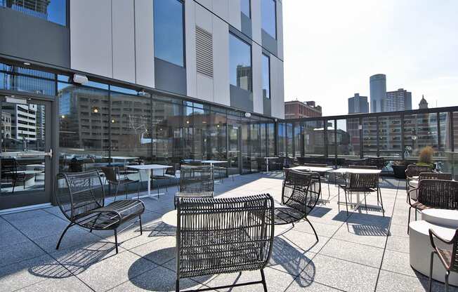 a rooftop patio with tables and chairs and a city in the background