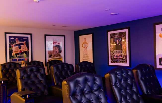 a theater room with blue lighting and leather chairs