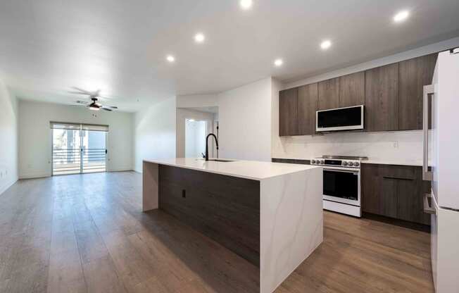 a kitchen and living room with white walls and wooden floors