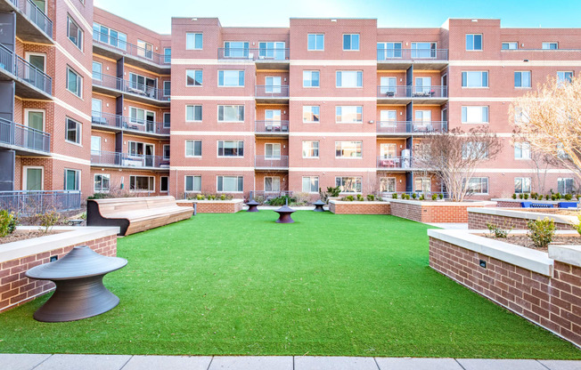 a courtyard with a green lawn in front of an apartment building