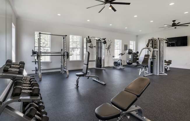 a large fitness room with exercise equipment and a flat screen tv