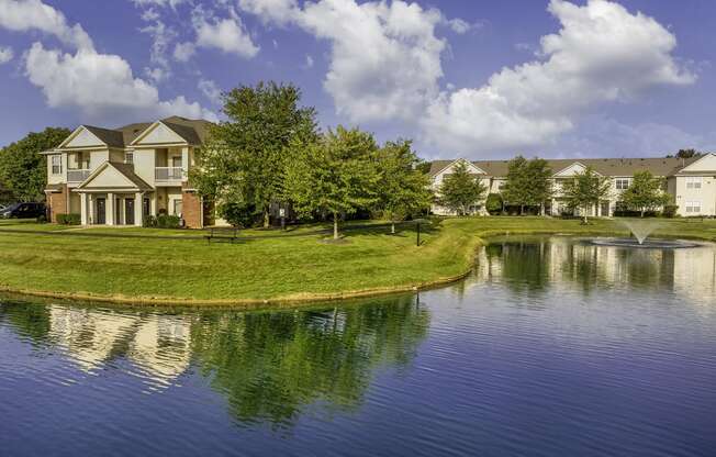 a pond in front of a house with a fountain