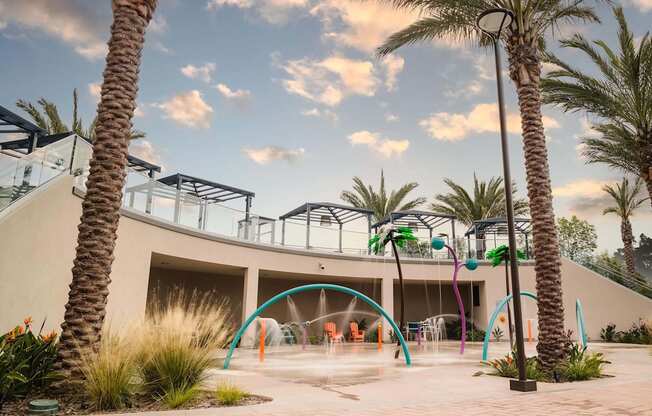 A playground with a slide and swings surrounded by palm trees.