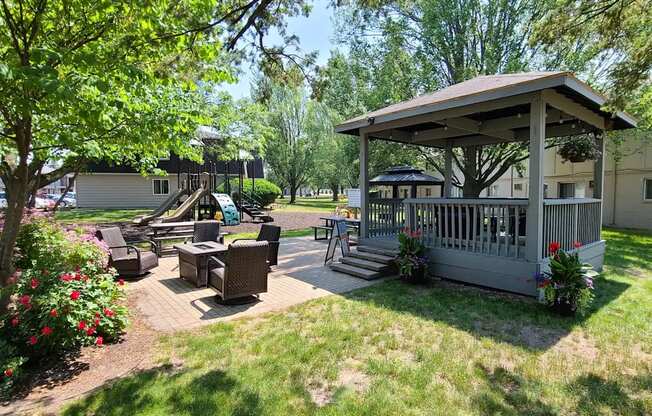 A gazebo is surrounded by a lawn and trees.