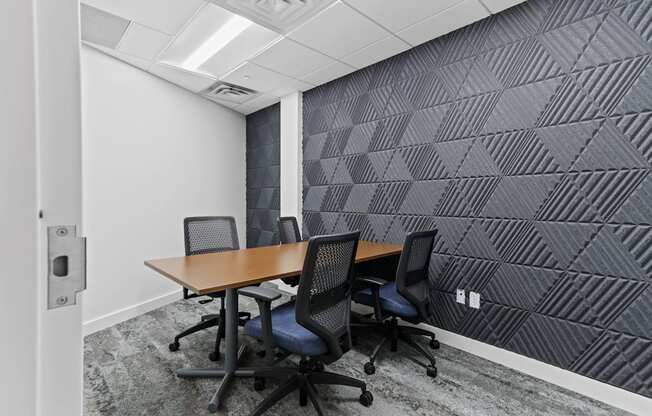 a small meeting room with a wooden table and four black chairs