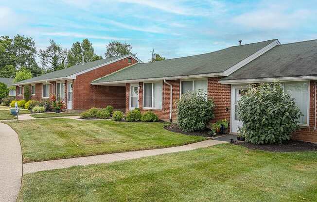 A row of houses with green lawns and trees in the background.