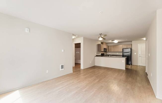 A spacious living room with a kitchen in the background.