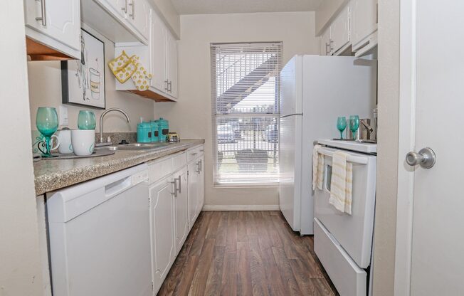 A kitchen with white appliances and wooden floors at The Drake in Bossier City, LA