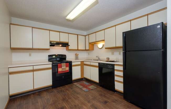 a kitchen with black and white appliances. Fargo, ND Twin Parks Apartments.