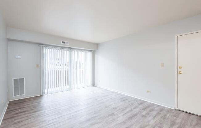 A large, empty room with a sliding door and wooden flooring.