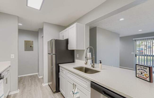 A modern kitchen with a black refrigerator and white countertops.
