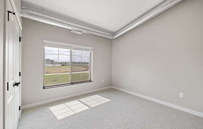 A room with a large window and a carpeted floor.