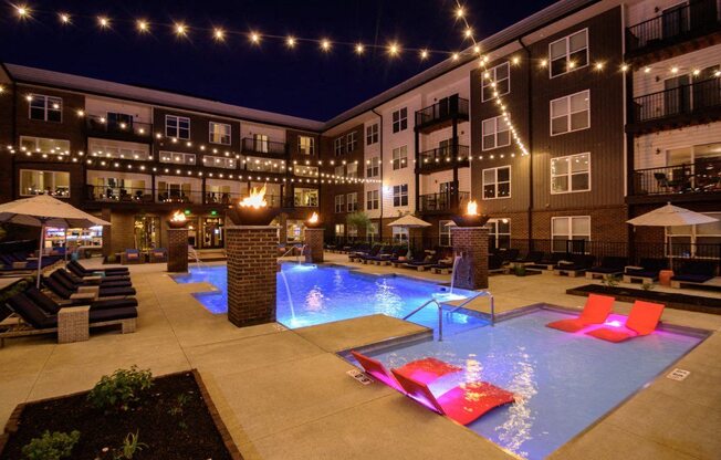 the pool is lit up at night at the apartments