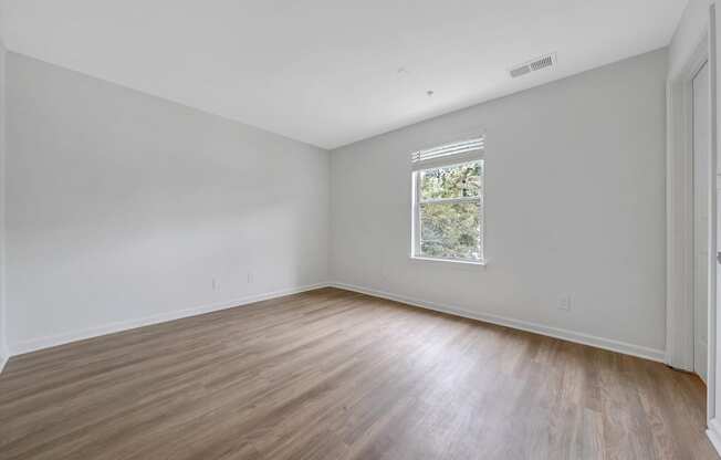 a bedroom with white walls and hardwood floors