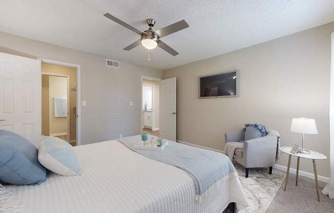 A bedroom with a bed, chair, and ceiling fan.